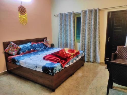 a bedroom with a bed with colorful pillows and a window at Anandam Home Stay in Rishīkesh