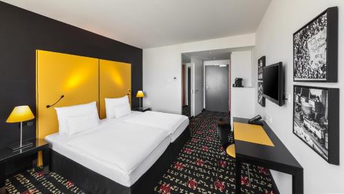 ミュンヘンにあるホリデイ イン ミュンヘン - ヴェストパークの大型ベッドと黄色のヘッドボードが備わるホテルルームです。