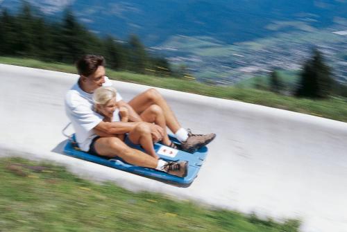 a man and woman riding aogie board down a road at Gourmet-Hotel Grünwald in Leogang