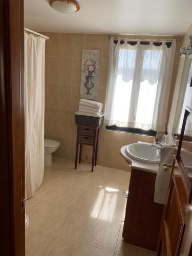 uma casa de banho com um lavatório, um WC e uma janela. em Casa rural Villa Abeleste em Fuentelisendo