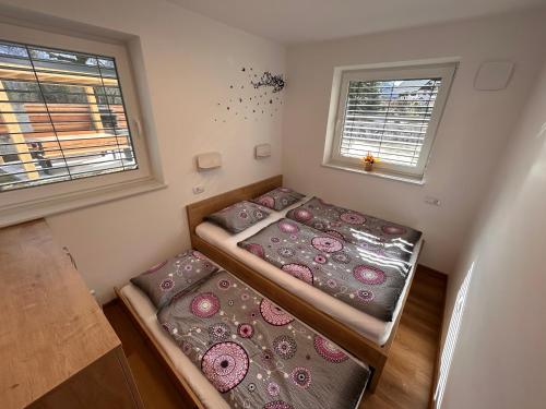 two beds in a small room with two windows at Apartmaji ENIA Rateče-Planica, Kranjska Gora in Kranjska Gora