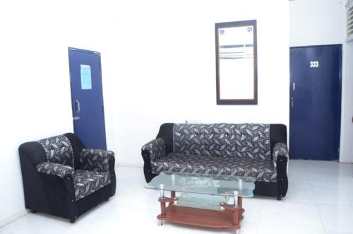 a couch and a chair and a table in a room at Hotel Sairam Lodge in Nashik