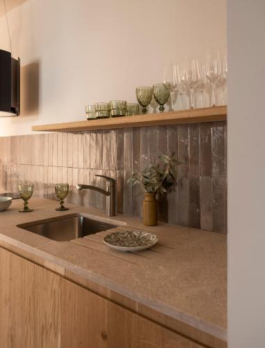 a kitchen counter with a sink and glasses on a shelf at Can Verí Suites in Sóller