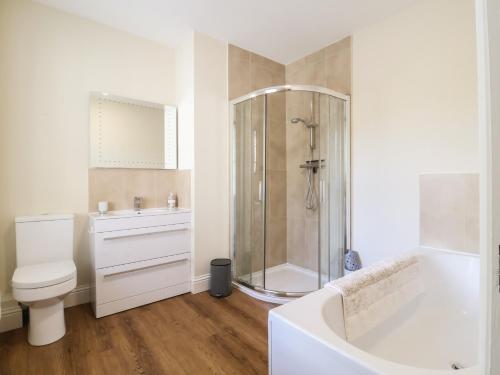 a white bathroom with a shower and a toilet at Henstead Hall East in Beccles