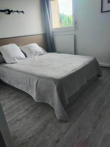 1 dormitorio con 1 cama con manta y ventana en Hôtel Bon Repos en Barbezieux