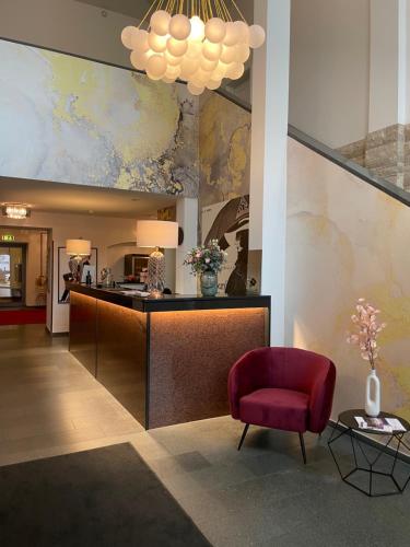 a lobby with a reception desk and a red chair at Batschari Palais Baden-Baden in Baden-Baden