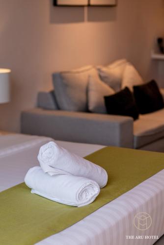 two towels on a bed in a room with a couch at The Aru Hotel at Aru Suites in Kota Kinabalu