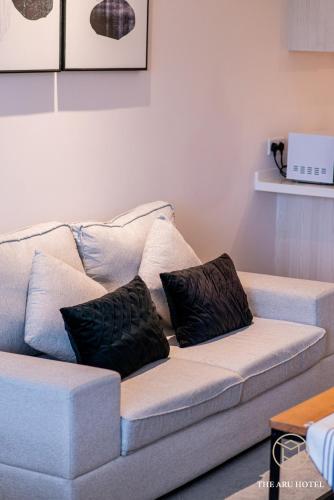 a white couch with two black pillows on it at The Aru Hotel at Aru Suites in Kota Kinabalu