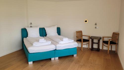 a bedroom with a blue bed with white pillows at Hotel Lethehof in Wardenburg