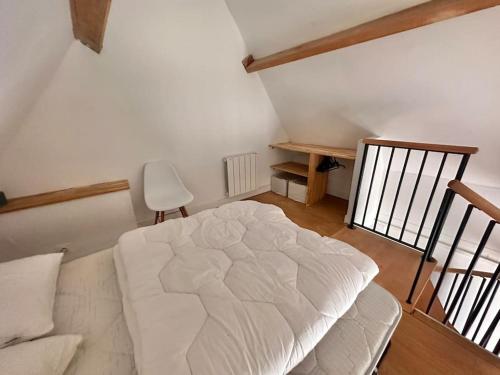 um quarto com uma cama branca e uma cadeira em Romantique petite chaumière près de Guérande em Saint-Lyphard