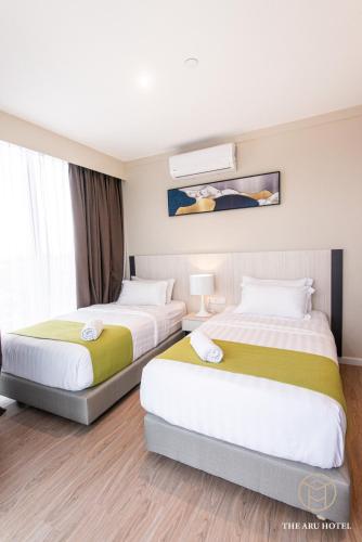 two beds in a hotel room with avertisement for at The Aru Hotel at Aru Suites in Kota Kinabalu