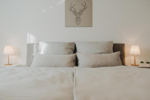 uma cama branca com lençóis e almofadas brancos em Penthousewohnung Bockhorn em Bockhorn