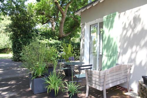 a patio with a table and chairs and plants at La petite chaumine in Saint-Nazaire