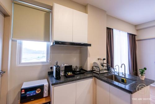 a small kitchen with a sink and a microwave at The Aru Hotel at Aru Suites in Kota Kinabalu