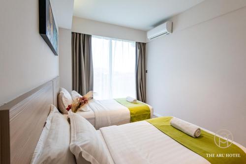 a hotel room with two beds and a window at The Aru Hotel at Aru Suites in Kota Kinabalu