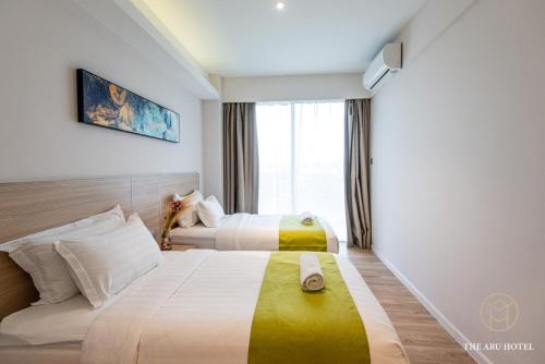 a hotel room with two beds and a window at The Aru Hotel at Aru Suites in Kota Kinabalu