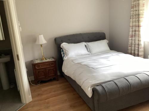 a bedroom with a bed and a table with a lamp at 4 Cois Glaisin View in Kilcarn