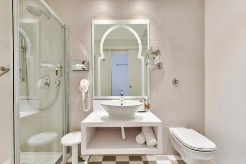 db San Antonio Hotel + Spa All Inclusive في خليج سانت بول: حمام مع حوض ومرحاض ومرآة