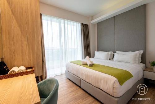 a hotel room with a large bed and a window at The Aru Hotel at Aru Suites in Kota Kinabalu