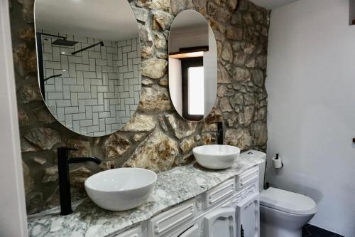 baño con 2 lavabos y pared de piedra en Casa El Acebal en Llanes