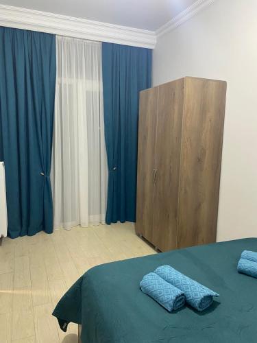 a bedroom with blue curtains and a bed and a wooden cabinet at All seasons in Gonio beach in Gonio