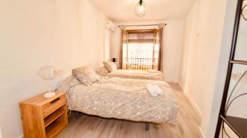1 dormitorio con 2 camas, mesa y ventana en PRECIOSO PISO EN PLENO CENTRO Con PARKING OPCIONAL en Granada