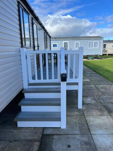 a white bench sitting on the steps of a house at Oscars caravan in Abergele