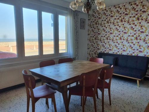 - une salle à manger avec une table, des chaises et un canapé bleu dans l'établissement villa cocomouette vue mer, à Le Portel