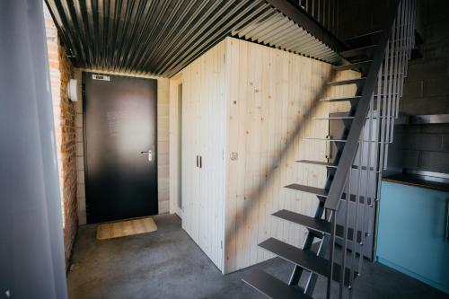 a hallway with a black door and a staircase at Smaltovňa Lofty in Lučenec