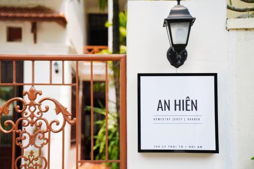 un panneau sur un mur à côté d'une porte et d'une lanterne dans l'établissement An Hiên Homestay Hội An, à Hội An