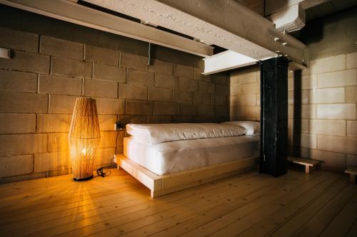 a bed in a room with a lamp on a wooden floor at Smaltovňa Lofty in Lučenec