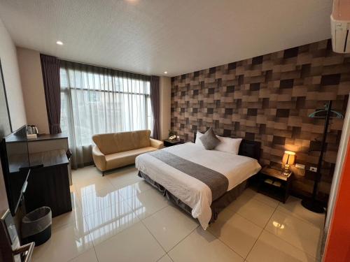 een slaapkamer met een bed en een bank in een kamer bij Boston Plus Hotel in Chiayi City