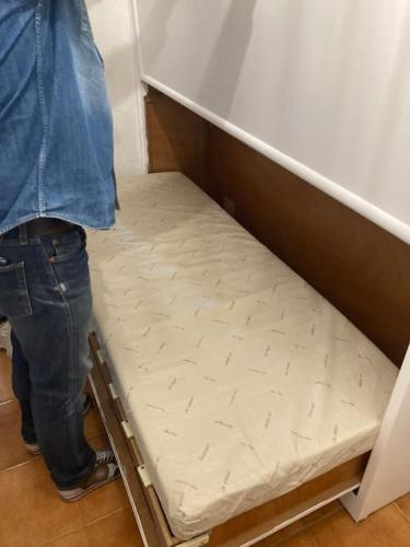 a person standing next to a bed in a room at Le Lavandou 6 pers. + parking privé + terrasse (au calme) in Le Lavandou