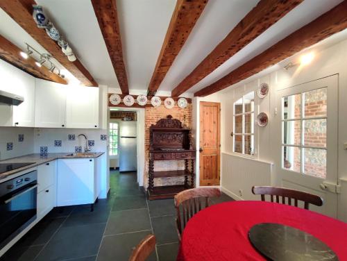 une cuisine avec des placards blancs et une table rouge dans l'établissement Domaine du Château de Briquedalles, à Sassetot-le-Mauconduit