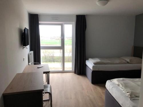 a hotel room with two beds and a desk and a window at FirstSleep Landshut in Landshut