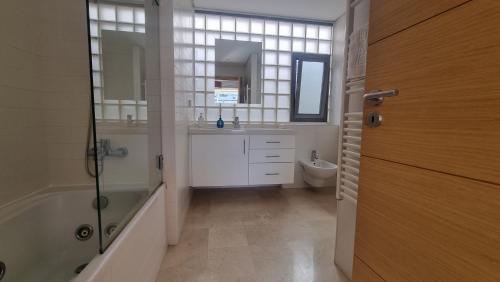 a bathroom with a tub and a sink and a toilet at Penthouse in private complex by Homekeys in Tavira