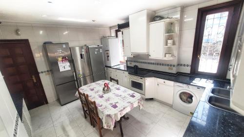 cocina con mesa y lavadora en TUUL ETXEA, Habitación en caserío a 8km de Bilbao, Baño compartido, en Galdakao