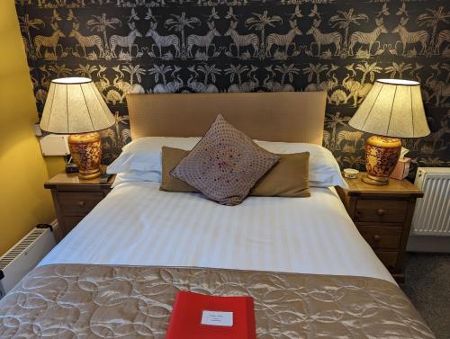 a bed with two lamps and a red book on it at Abingdon House in Torquay