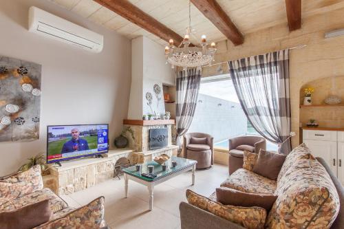 a living room with a couch and a tv at Twilight Gozitan Farmhouse With Pool - Happy Rentals in Għammar