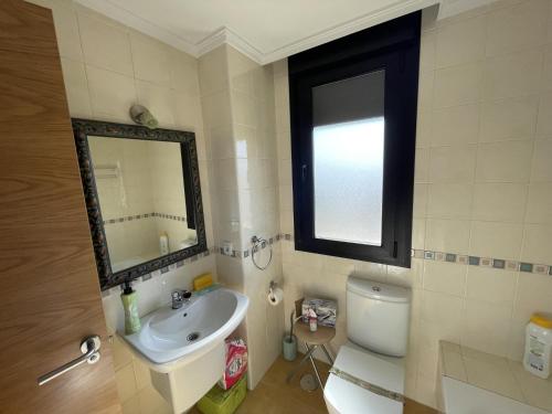 uma casa de banho com um lavatório, um WC e um espelho. em Amplio apartamento con Garaje em Suances