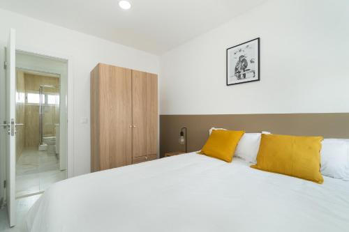 1 dormitorio con 1 cama blanca grande con almohadas amarillas en Estrela Do Mar Apartment by Olala Homes en Cascais