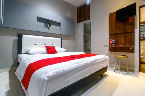 um quarto com uma cama grande e um cobertor vermelho em RedDoorz near Kebon Jeruk Jakarta em Jakarta