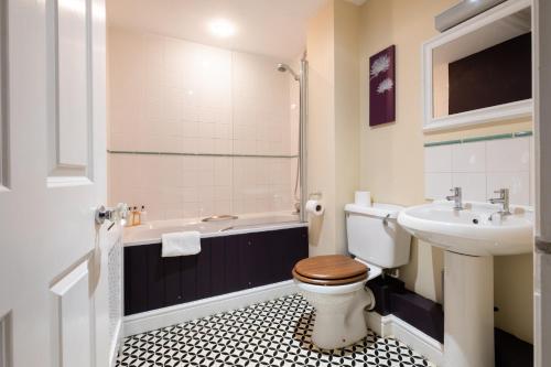 a bathroom with a toilet and a sink and a tub at White Hart Inn in Blythburgh