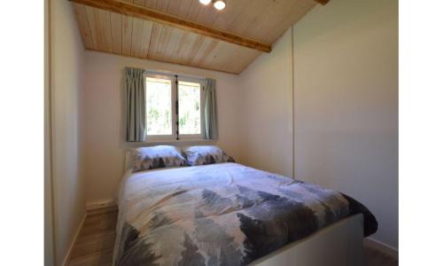 Cama en habitación pequeña con ventana en Bungalow aan de Visbeekvallei, en Vlimmeren