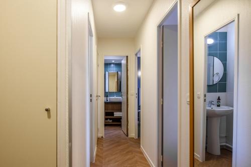 a hallway of a bathroom with a sink and a mirror at Aparthotel Adagio Paris Buttes Chaumont in Paris