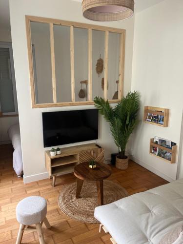 een woonkamer met een flatscreen-tv en een tafel bij Studio «  La Mouette Rieuse » in Le Touquet-Paris-Plage