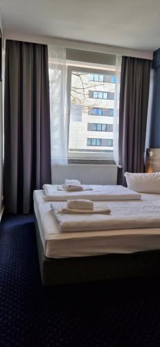 2 bedden in een hotelkamer met een raam bij Hotel Mercedes/Centrum in Hamburg