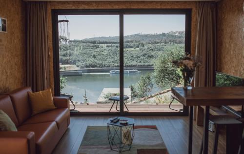 a living room with a couch and a large window at Medronho D'Ouro bungalows in Foz do Sousa
