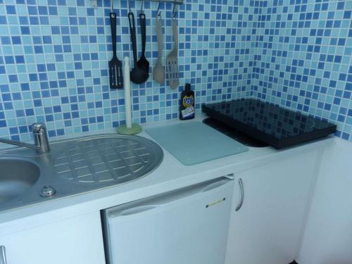 - un comptoir de cuisine avec évier et un mur carrelé bleu dans l'établissement Studio au bord de l'eau avec parking privé et WiFi - FR-1-308-64, au Lavandou