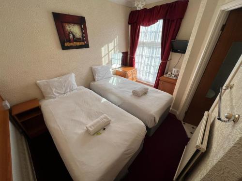 two beds in a hotel room with towels on them at Fjaerland Hotel in Great Yarmouth